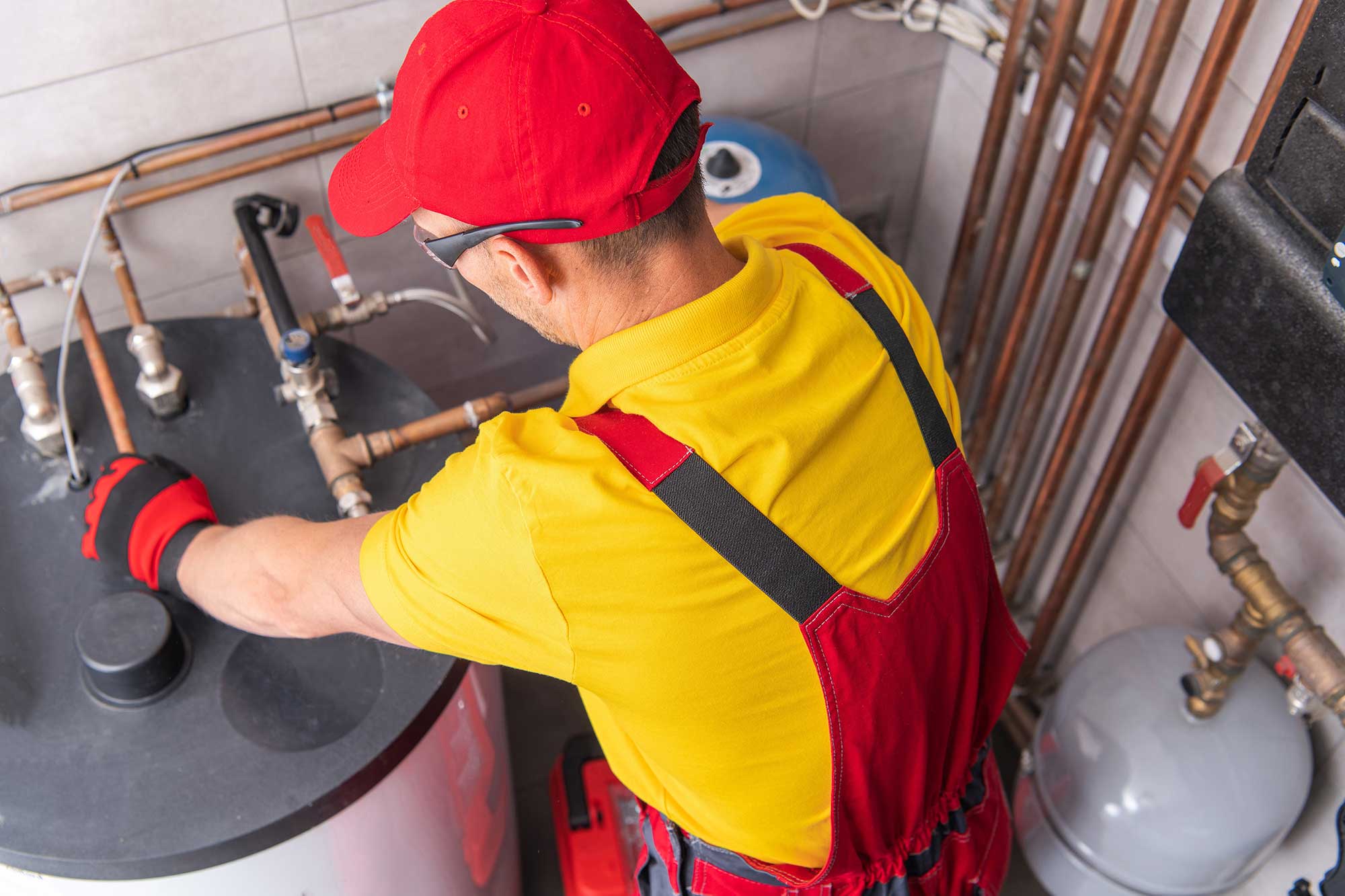 Technician performing water heater repair and maintenance on a home water heater.