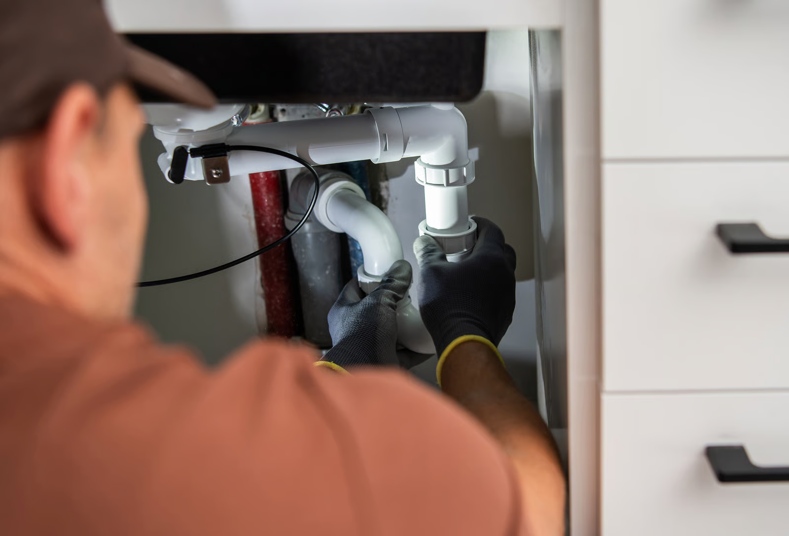 Plumbing fixture repair under sink with visible pipe leak.